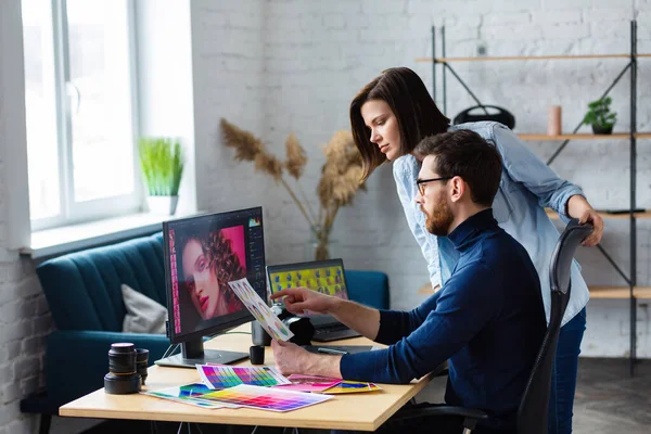 Fotograf och grafisk formgivare arbetar på kontoret med laptop, monitor, grafisk ritplatta och färgpalett. Skapa team diskuterar idéer i reklambyrå. Retuscherar bilder. Lagarbete — Stockfoto