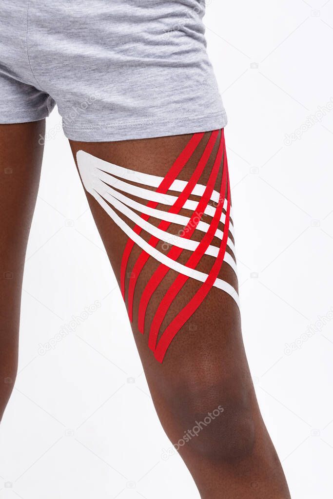 Close up view of kinesiology tape on patient hip.Kinesiology taping. Young female African American athlete.Post traumatic rehabilitation,sport physical therapy,recovery concept,alternative medicine