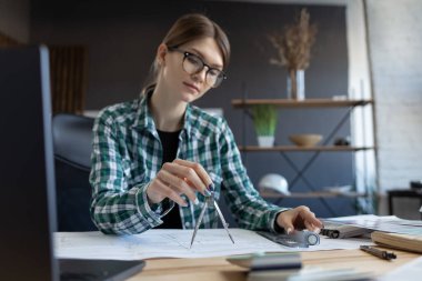 Mimar ofiste planlar çiziyor. Mühendis bir inşaat projesi çiziyor. Mimari plan. İşine odaklanmış güzel bir kadının yakın plan portresi. İş inşa kavramı