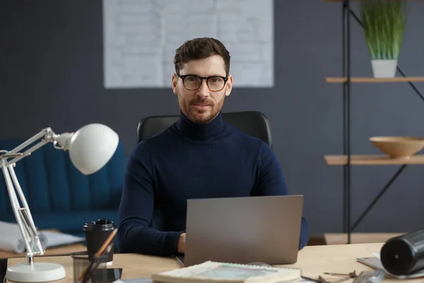 Arquitecto trabajando en oficina con laptop. Retrato de negocios de un hombre barbudo guapo con anteojos sentados en el trabajo. Un hombre de negocios seguro tuvo éxito. Concepto empresarial — Foto de Stock