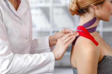 Kinesiology taping. Physical therapist applying kinesiology tape to patient neck. Therapist treating injured trapezius muscles of young athlete. Post traumatic rehabilitation, sport physical therapy clipart