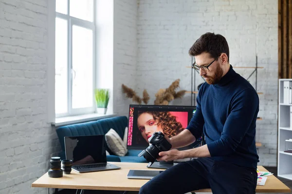 Portrait of professional photographer holding camera in photo studio. Workplace in office with camera, laptop, monitor, graphic drawing tablet and color palette. Retouching images. Creative agency — Stock Photo, Image