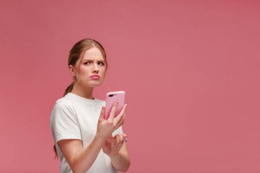 Kafası karışmış, elinde pembe akıllı telefon tutan genç bir kadın. Utangaç bir kız cep telefonunun bozuk olmasıyla ilgili sorun yaşıyor. Kötü haber ya da e-posta, spam mesajı alıyor.