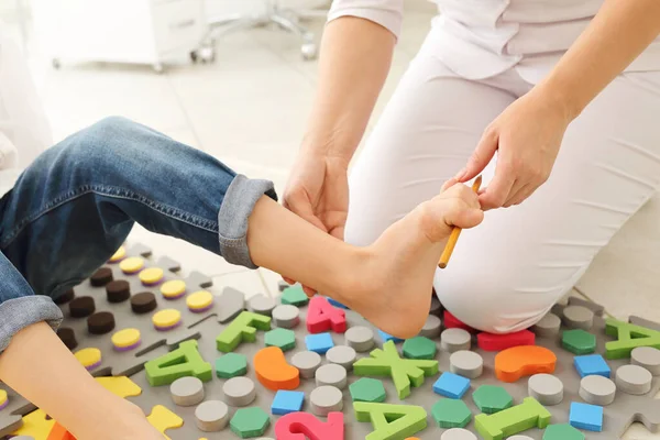 Leczenie dzieci płaskostopie za pomocą specjalnego dywanu masażu.Mała dziewczynka na macie masażu robi ćwiczenia dla profilaktyki płaskostopiej.Ćwiczenia wzmacniające stopy.Podiatry klinika — Zdjęcie stockowe