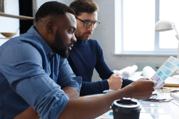 Equipo de ingenieros multirraciales trabajando en la oficina con paleta de colores. Los arquitectos seleccionan colores para la construcción utilizando muestras de color, bocetos y proyectos de construcción de planificación. Socios discutiendo en el trabajo — Foto de Stock