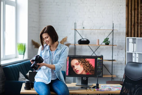 Portret van een professionele fotograaf met camera in de fotostudio. Werkplaats in het kantoor met camera, laptop, monitor, grafische tablet en kleurenpalet. Terugtrekken van beelden. Creatief agentschap — Stockfoto