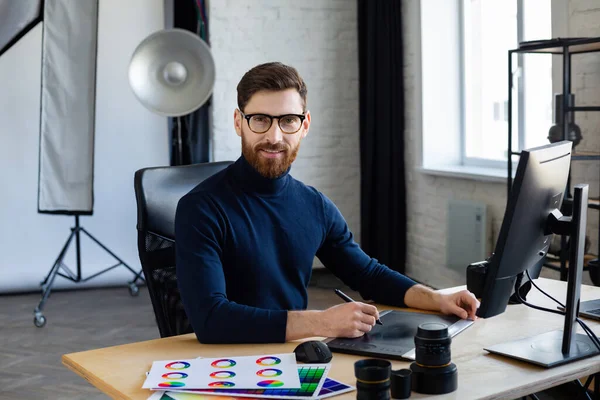 Retoucheren van beelden in speciaal programma.Portret van grafisch ontwerper die werkt in het kantoor met laptop, monitor, grafische tablet en kleurpalet.Retoucher werkplek in fotostudio.Creative agency — Stockfoto