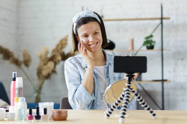Jonge vrouwelijke blogger het opnemen van een tutorial video voor haar schoonheid blog over cosmetica.Vlogger testen gezichtscrème en live video uit te zenden naar het sociale netwerk thuis. — Stockfoto