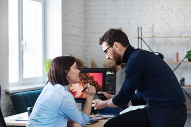 Ofiste dizüstü bilgisayar, monitör, grafik çizim tableti ve renk paleti ile çalışan fotoğrafçı ve grafik tasarımcısı. Reklam ajansında fikirleri tartışan bir ekip yaratmak. Görüntüler alınıyor. Takım çalışması.