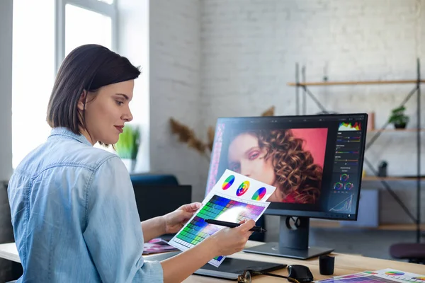 Ofiste dizüstü bilgisayar, monitör, grafik çizim tableti ve renk paleti ile çalışan grafik tasarımcısının portresi. Özel programda resimler alınıyor. Fotoğraf stüdyosunda iş yeri alınıyor. Yaratıcı ajans