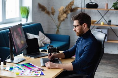 Özel programdaki resimler alınıyor. Dizüstü bilgisayar, monitör, grafik çizim tableti ve renk paleti ile çalışan grafik tasarımcısının portresi. Fotoğraf stüdyosundaki çalışma yeri. Yaratıcı ajans
