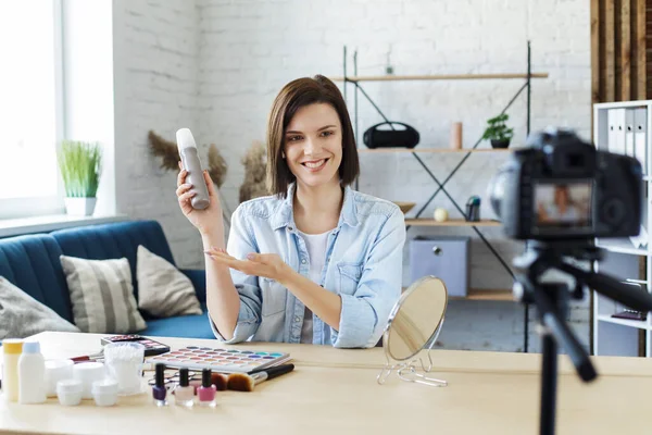 Young female blogger recording a tutorial video for her beauty blog about cosmetics.Vlogger testing hair spray and broadcast live video to social network at home.Blogging, videoblog, makeup concept — Stock Photo, Image