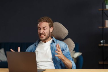 Dizüstü bilgisayar kullanan sinirli, genç, kıvırcık adam. Stresli serbest çalışan biri, çalışmayan dizüstü bilgisayarında veri kaybetmiş. Kötü haber ya da e-posta alınıyor, spam mesajı. Mobil aygıtlarla çalışan gençler