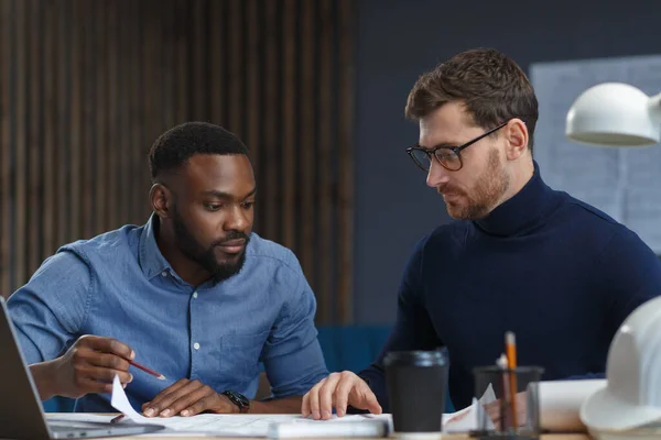 Equipe d'ingénieurs multiraciaux travaillant au bureau avec des plans et du matériel d'architecte esquissant, discutant et planifiant le projet de construction. Partenaires contestant au travail. Concept de construction d'entreprise — Photo