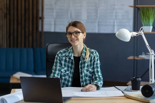 Diseñadora de interiores femenina trabajando en oficina con laptop. Arquitecto reflexiona sobre el plan arquitectónico, buscando nuevas ideas para el proyecto de construcción. Mujer sentada en el lugar de trabajo. Concepto de retrato empresarial —  Fotos de Stock