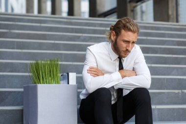 Beyaz gömlekli mutsuz genç bir yönetici işinden kovuldu. Üzgün bir işçi işten çıkarmalardan sonra bir iş merkezinin merdivenlerinde oturur. Kriz ve işsizlik