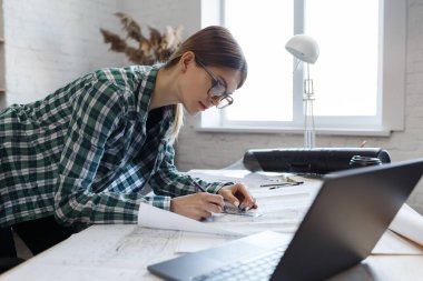 Mimar ofiste planlar çiziyor. Mühendis bir inşaat projesi çiziyor. Mimari plan. İşine odaklanmış güzel bir kadının yakın plan portresi. İş inşa kavramı