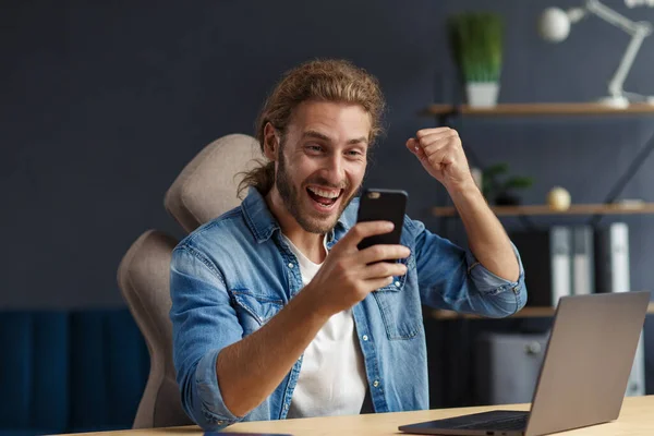 Joven usando smartphone y sonriendo. Feliz hombre de negocios utilizando aplicaciones de teléfono móvil, mensaje de texto, navegación por Internet, mirando el teléfono inteligente. Concepto de jóvenes que trabajan con dispositivos móviles — Foto de Stock