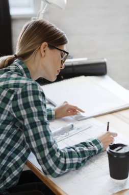 Mimar ofiste planlar çiziyor. Mühendis bir inşaat projesi çiziyor. Mimari plan. İşine odaklanmış güzel bir kadının yakın plan portresi. İş inşa kavramı