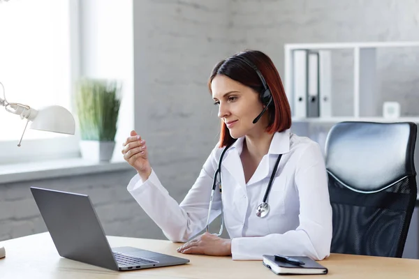 Femme médecin consulte par appel vidéo. Assistance médicale en ligne. Vidéoconférence des professionnels de la santé. Portrait d'un médecin sur le lieu de travail.Concept de conversation patient-médecin — Photo