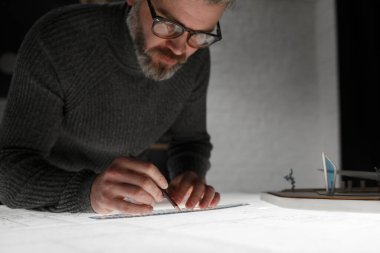 Mimar ofiste planlar çiziyor. Mühendis bir inşaat projesi çiziyor. Mimari plan. Yakışıklı sakallı adamın işine odaklanmış yakın plan portresi. İş inşa kavramı