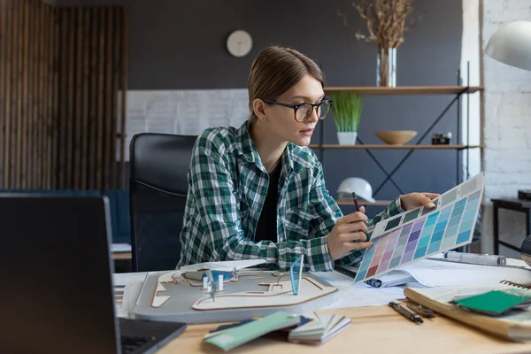 Diseñadora de interiores femenina trabajando en oficina con paleta de colores. Arquitecto seleccionar colores para la construcción utilizando muestras de color, la búsqueda de nuevas ideas para el proyecto. Retrato de mujer hermosa en el lugar de trabajo — Foto de Stock