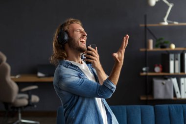 Uzun saçlı, kulaklıklı, müzik dinleyen, şarkı söyleyen, dans eden, kulaklıklı, komik, duygusal, gülümseyen adam. Evde rahat ol. Müzik dinlemenin tadını çıkar. Stres yönetimi.