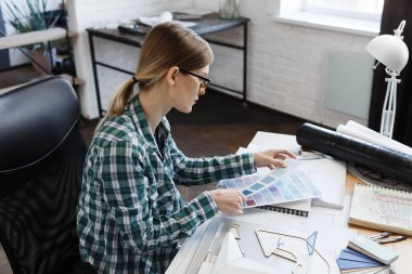 Renk paletinde çalışan kadın iç mimar. Renk örnekleri kullanarak, proje için yeni fikirler arayarak inşa etmek için renkleri seçin. İş yerinde güzel bir kadının portresi.
