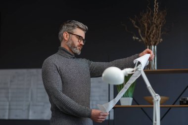 Ofiste planlarla çalışan bir mimar. Mühendis mimari planı inceliyor, bir inşaat projesi çiziyor. İş yerinde oturan sakallı yakışıklı bir adamın portresi. İş inşa kavramı