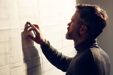 Çalışmaya odaklanmış yakışıklı bir adamın yakın plan portresi. Ofiste planlarla çalışan bir mimar. Mühendis bir inşaat projesi çiziyor. Mimari plan. İş inşa kavramı