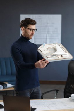 Ofiste çalışan mimar 3D model bir bina. Mühendis bina planını inceliyor, inşaat projesi için yeni fikirler arıyor. İş yerindeki yakışıklı sakallı adam. İş inşa kavramı