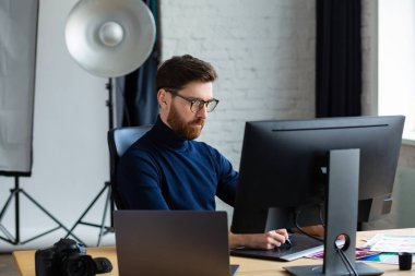 Özel programdaki resimler alınıyor. Dizüstü bilgisayar, monitör, grafik çizim tableti ve renk paleti ile çalışan grafik tasarımcısının portresi. Fotoğraf stüdyosundaki çalışma yeri. Yaratıcı ajans