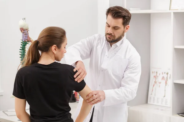 Médico masculino examinando paciente femenina que sufre de dolor de codo. Examen médico. Quiropráctica, osteopatía, rehabilitación postraumática, fisioterapia deportiva. Medicina alternativa, concepto de alivio del dolor —  Fotos de Stock