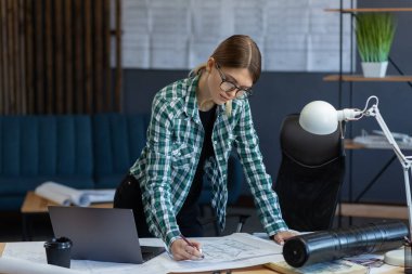 Ofiste planlarla çalışan iç mimar. Mühendis mimari planı inceliyor, bir inşaat projesi çiziyor. İş yerinde güzel bir kadının portresi. İş inşa kavramı