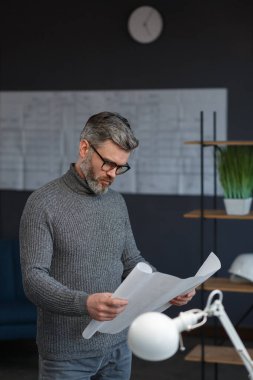 Ofiste planlarla çalışan bir mimar. Mühendis mimari planı inceliyor, bir inşaat projesi çiziyor. İş yerinde oturan sakallı yakışıklı bir adamın portresi. İş inşa kavramı