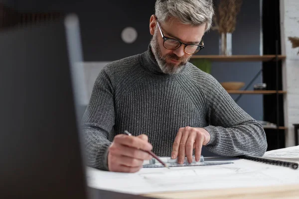 Architect tekent blauwdrukken in functie. Ingenieur schetst een bouwproject. Architectuurplan. Close-up portret van knappe bebaarde man geconcentreerd op het werk. Bedrijfsbouwconcept — Stockfoto