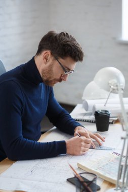 Ofiste planlarla çalışan bir mimar. Mühendis mimari planı inceliyor, bir inşaat projesi çiziyor. İş yerinde oturan sakallı yakışıklı bir adamın portresi. İş inşa kavramı