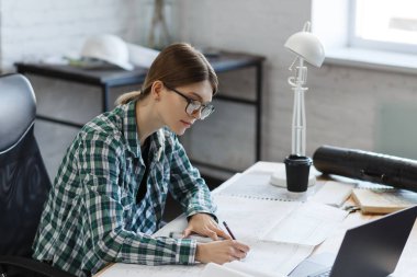 Mimar ofiste planlar çiziyor. Mühendis bir inşaat projesi çiziyor. Mimari plan. İşine odaklanmış güzel bir kadının yakın plan portresi. İş inşa kavramı
