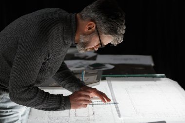 Mimar ofiste planlar çiziyor. Mühendis bir inşaat projesi çiziyor. Mimari plan. Yakışıklı sakallı adamın işine odaklanmış yakın plan portresi. İş inşa kavramı