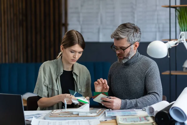 Equipo de interioristas trabajando en oficina con paleta de colores. Los arquitectos seleccionan colores para la construcción utilizando muestras de color, bocetos y proyectos de construcción de planificación. Socios discutiendo en el trabajo — Foto de Stock