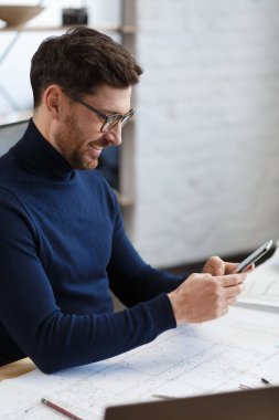 Genç adam akıllı telefon kullanıyor ve gülümsüyor. Mutlu iş adamı cep telefonu uygulamaları kullanıyor, mesaj atıyor, internette geziniyor, akıllı telefona bakıyor. Mobil aygıtlarla çalışan gençlerin kavramı