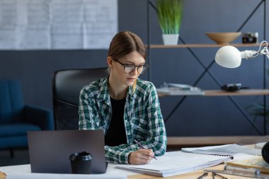Ofiste dizüstü bilgisayarla çalışan kadın iç mimar. Mimar mimari plan üzerinde düşünür, inşaat projesi için yeni fikirler arar. İş yerinde oturan bir kadın. İş portresi kavramı