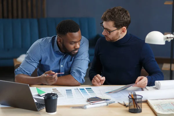 Equipo de ingenieros multirraciales trabajando en la oficina con paleta de colores. Los arquitectos seleccionan colores para la construcción utilizando muestras de color, bocetos y proyectos de construcción de planificación. Socios discutiendo en el trabajo — Foto de Stock