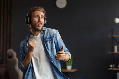 Uzun saçlı, kulaklıklı, müzik dinleyen, şarkı söyleyen, dans eden, kulaklıklı, komik, duygusal, gülümseyen adam. Evde rahat ol. Müzik dinlemenin tadını çıkar. Stres yönetimi.