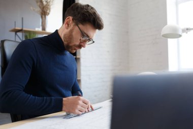 Ofiste planlarla çalışan bir mimar. Mühendis mimari planı inceliyor, bir inşaat projesi çiziyor. İş yerinde oturan sakallı yakışıklı bir adamın portresi. İş inşa kavramı