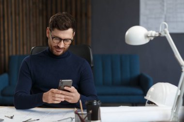 Genç adam akıllı telefon kullanıyor ve gülümsüyor. Mutlu iş adamı cep telefonu uygulamaları kullanıyor, mesaj atıyor, internette geziniyor, akıllı telefona bakıyor. Mobil aygıtlarla çalışan gençlerin kavramı