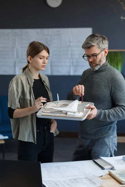 3d arquitectos equipo de trabajo en la oficina con el edificio modelo 3d. Los arquitectos inspeccionan el diseño del edificio, planifican el proyecto de construcción, buscan nuevas ideas. Socios discutiendo en el trabajo. Concepto empresarial — Foto de Stock