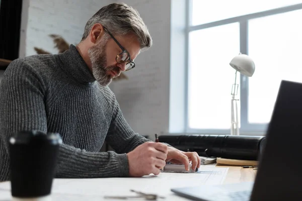 Arquitecto dibujando planos en la oficina. Ingeniero dibujando un proyecto de construcción. Plano arquitectónico. Retrato de primer plano del guapo barbudo concentrado en el trabajo. Concepto de construcción empresarial —  Fotos de Stock