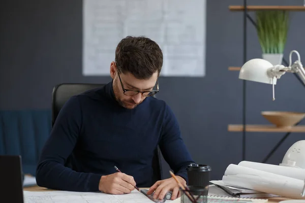 Arquitecto trabajando en la oficina con planos. Ingeniero inspeccionar plan arquitectónico, bosquejando un proyecto de construcción. Retrato de hombre barbudo guapo sentado en el lugar de trabajo. Concepto de construcción empresarial — Foto de Stock