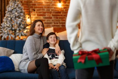 Anne babalar sevimli oğluna hediye paketi sunuyor. Noel çocukları, çocuk, portre. Mutlu bir aile Noel sabahı birlikte geçirir. Kış tatilleri, Noel kutlamaları, yeni yıl konsepti.